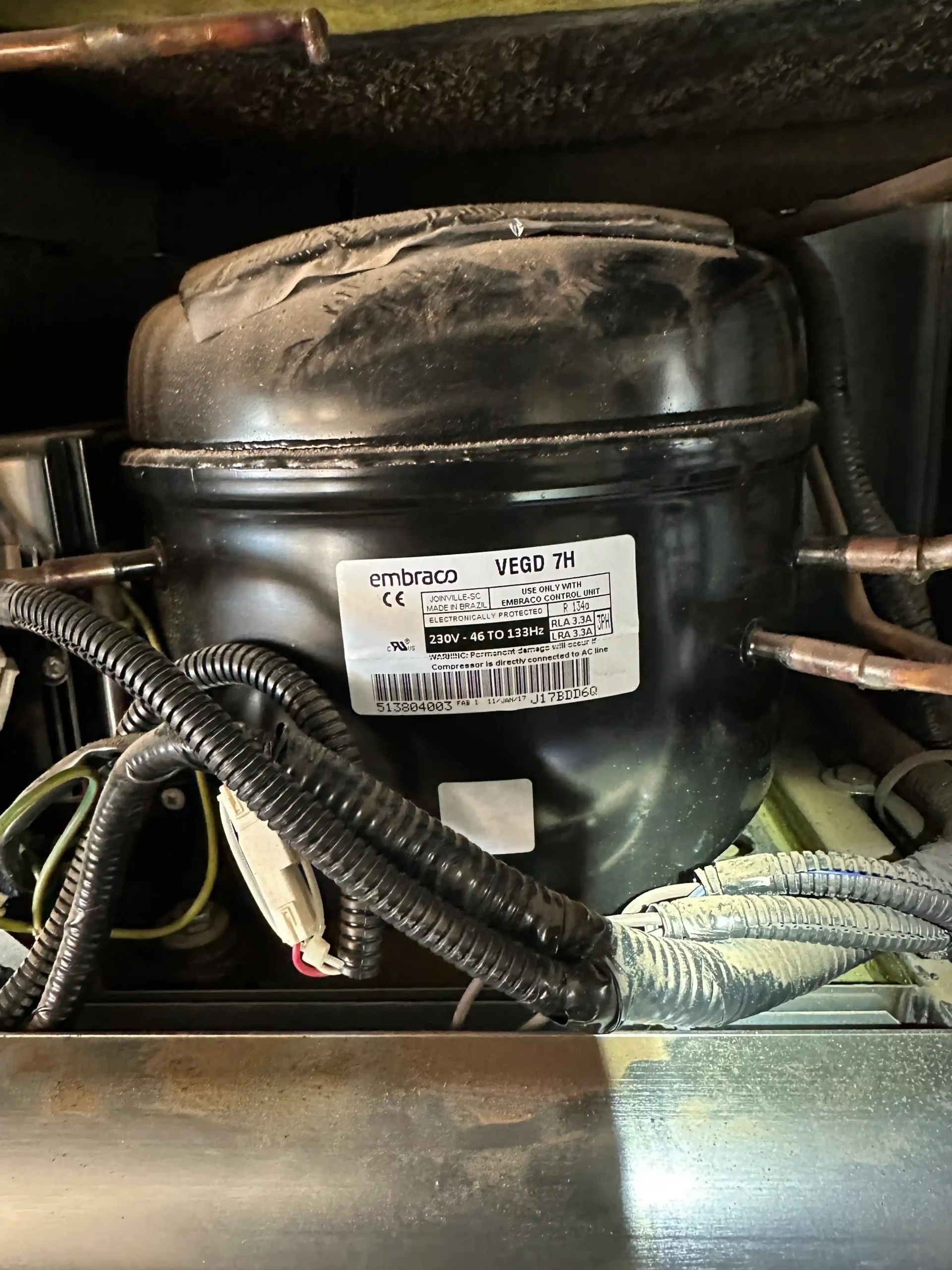 Rear compressor compartment of a refrigerator, showing a major sealed-system repair that can make replacement more practical.
